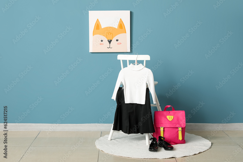 Chair with stylish school uniform, shoes and backpack near color wall in room