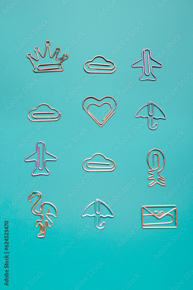 Paper clips in different shapes on blue background