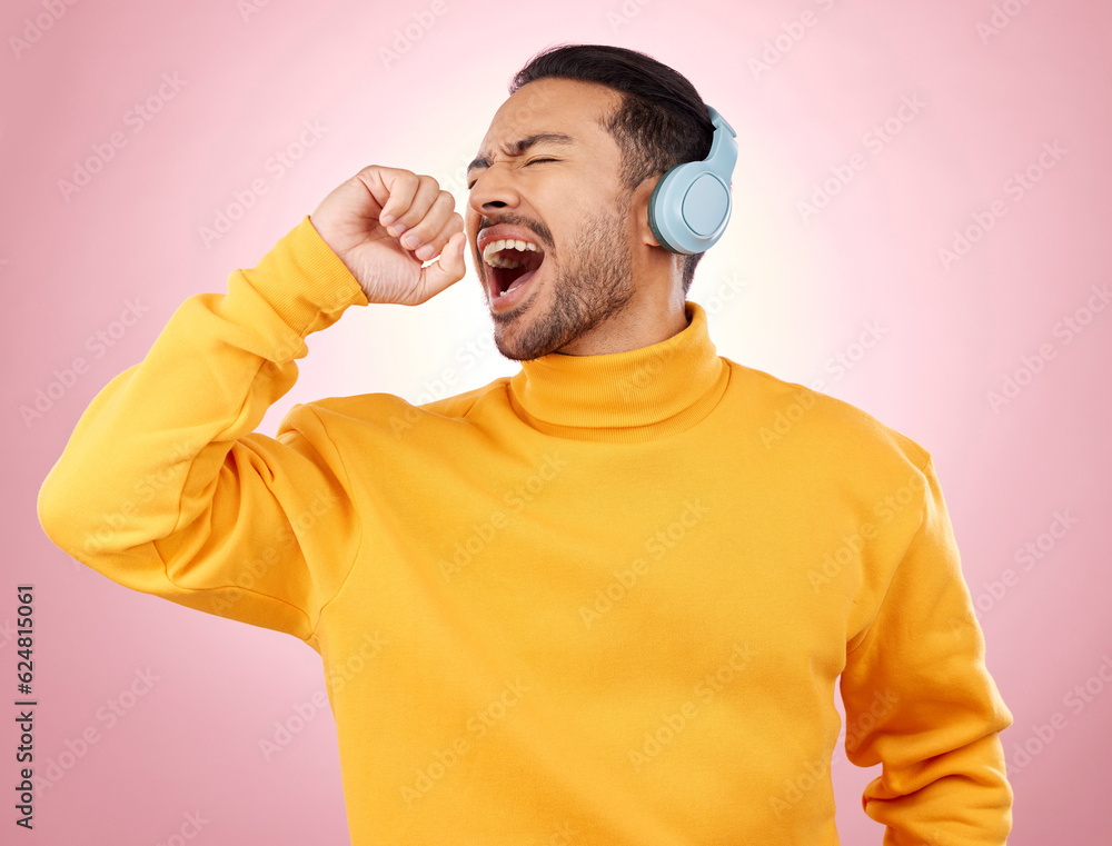 Asian man, headphones and listening to music for karaoke or singing against a pink studio background