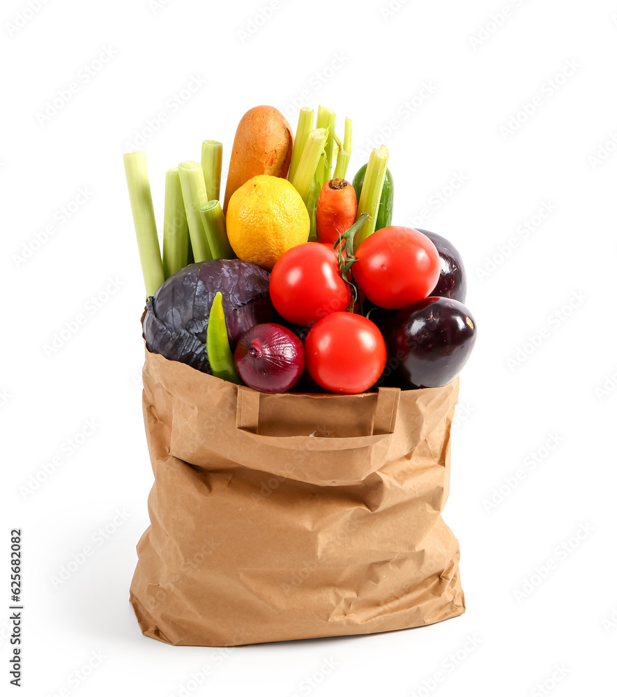 Paper bag full of fresh vegetables and baguette on white background
