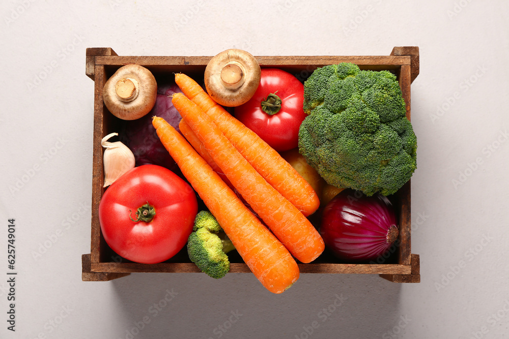 Wooden box with different fresh vegetables on white background