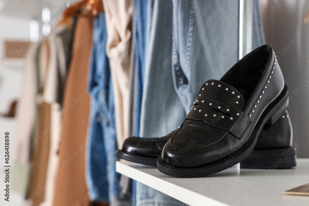 Stylish black shoes on shelf in boutique, closeup