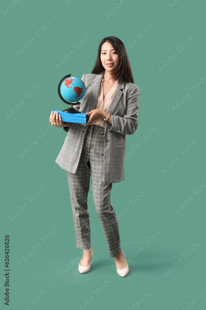 Asian Geography teacher with globe and books on green background