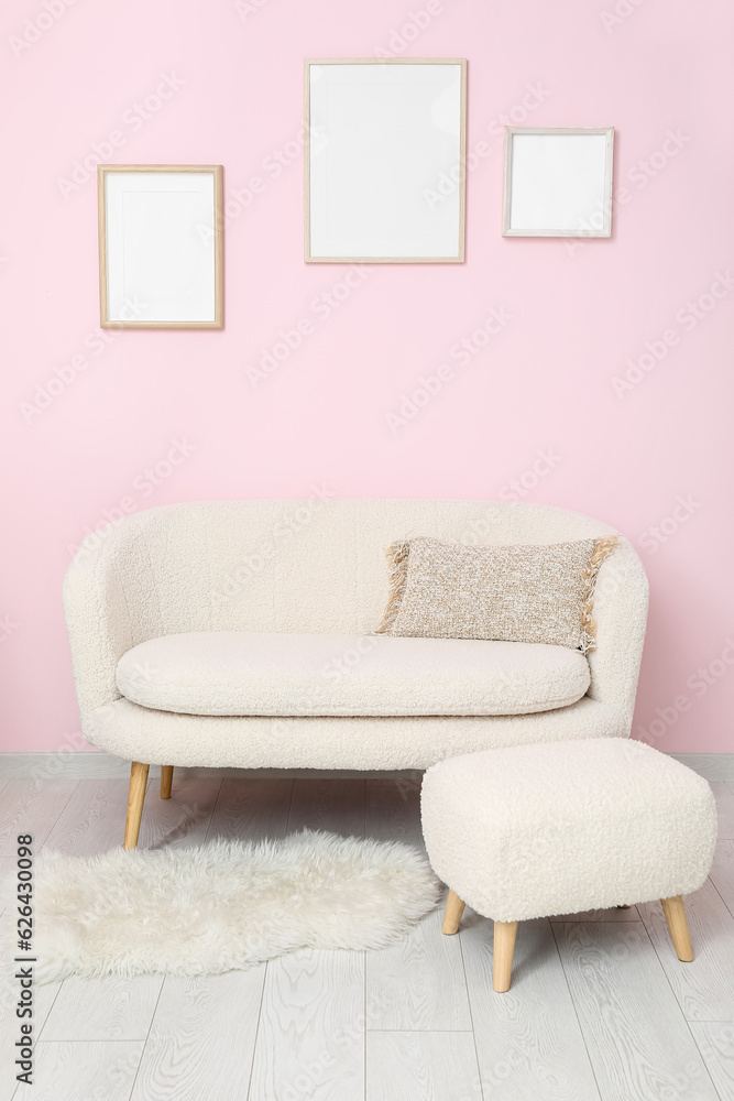 Interior of stylish living room with sofa and blank frames on pink wall