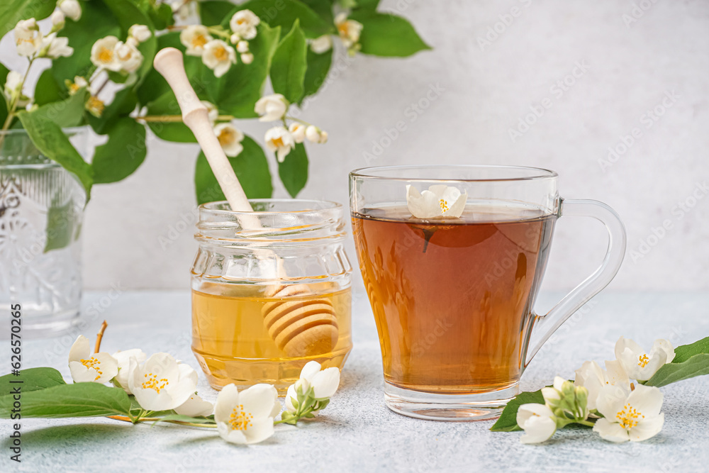 Cup of tea, honey and beautiful jasmine flowers on light background
