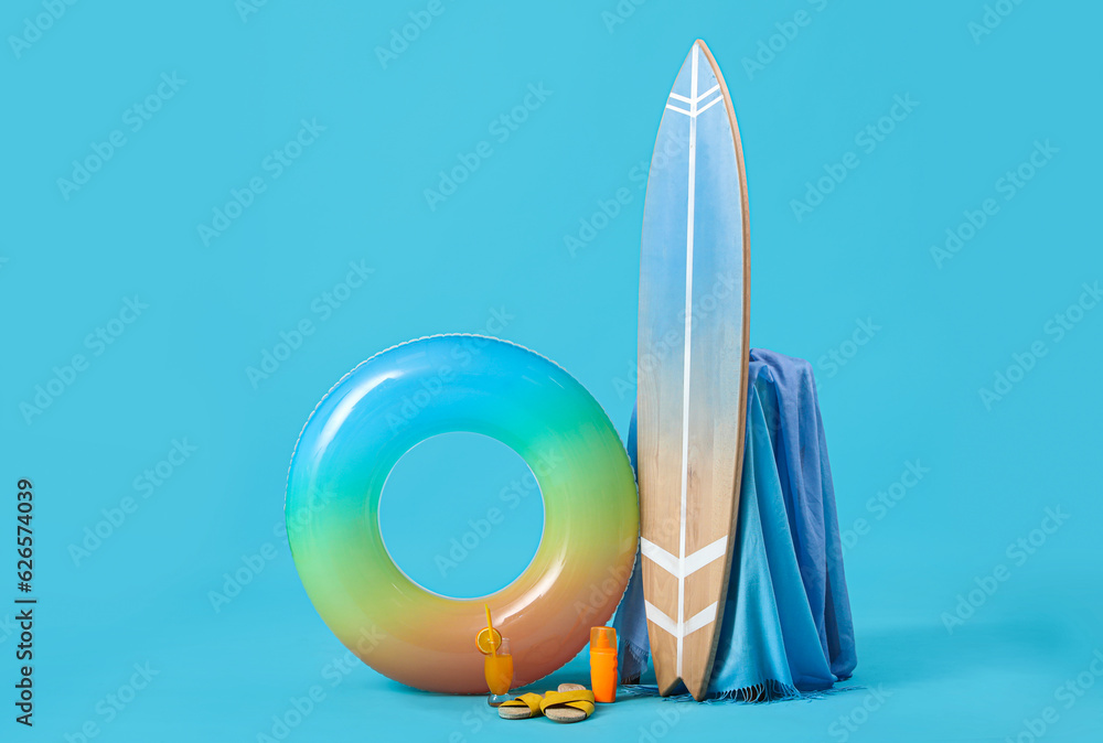 Beach accessories with swim ring and surfboard on blue background