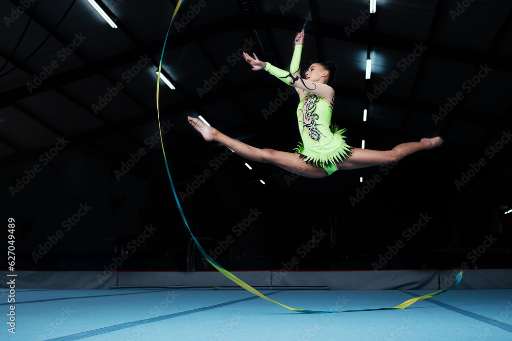 Jump, rhythmic gymnastics and woman in gym with ribbon, creative sport or action, performance or fit