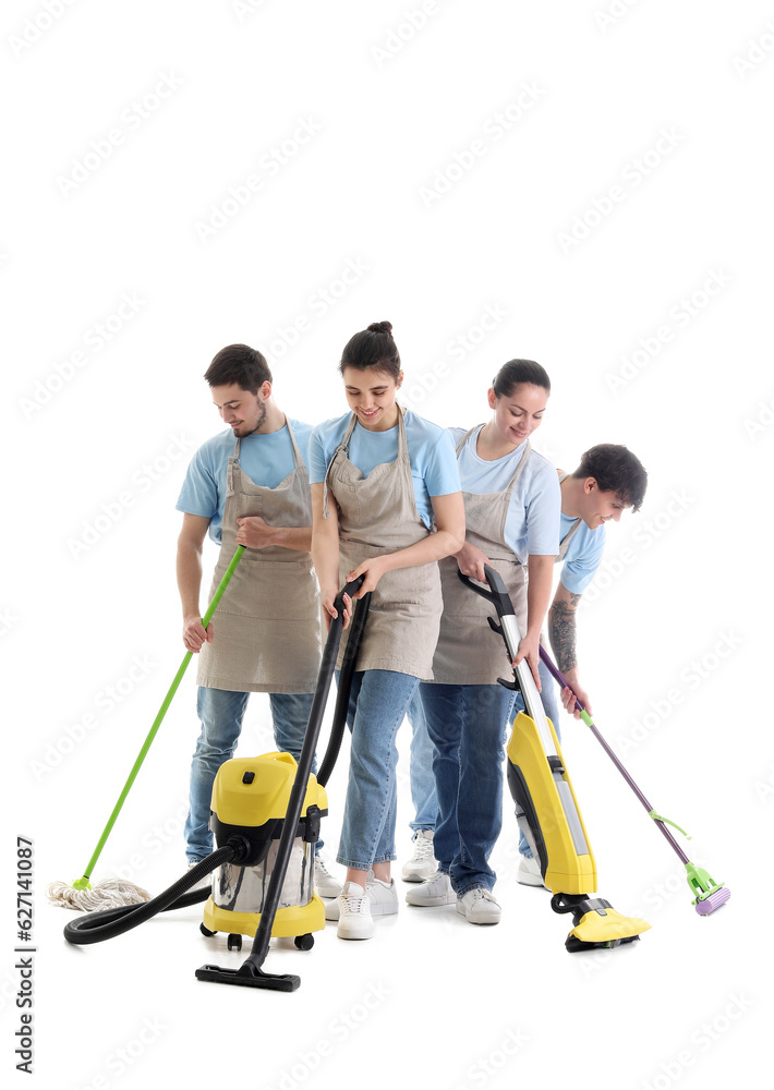 Young janitors with cleaning supplies on white background