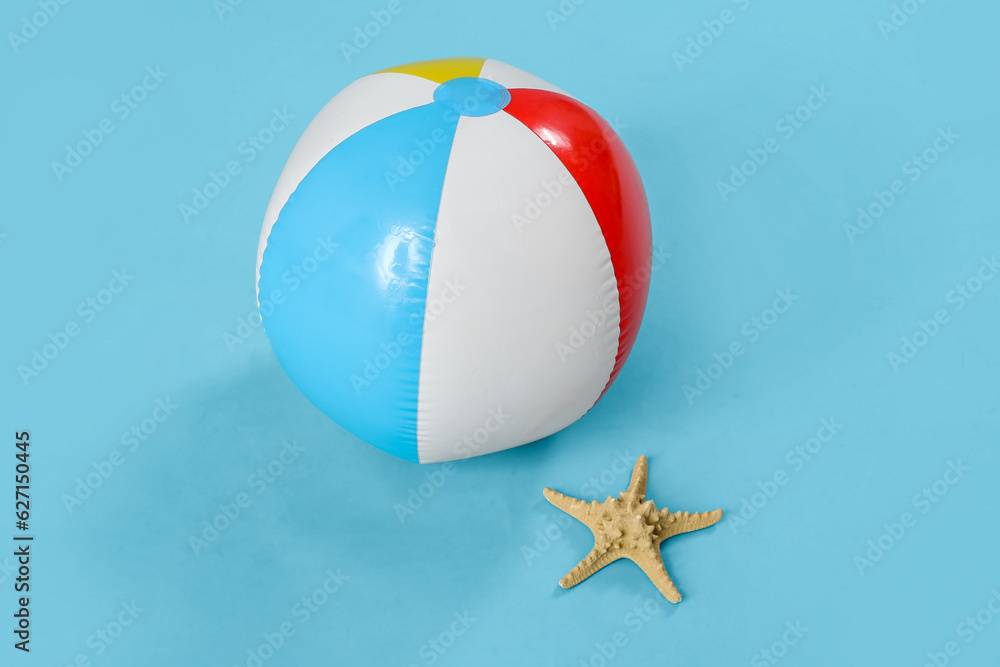 Inflatable beach ball and starfish on blue background