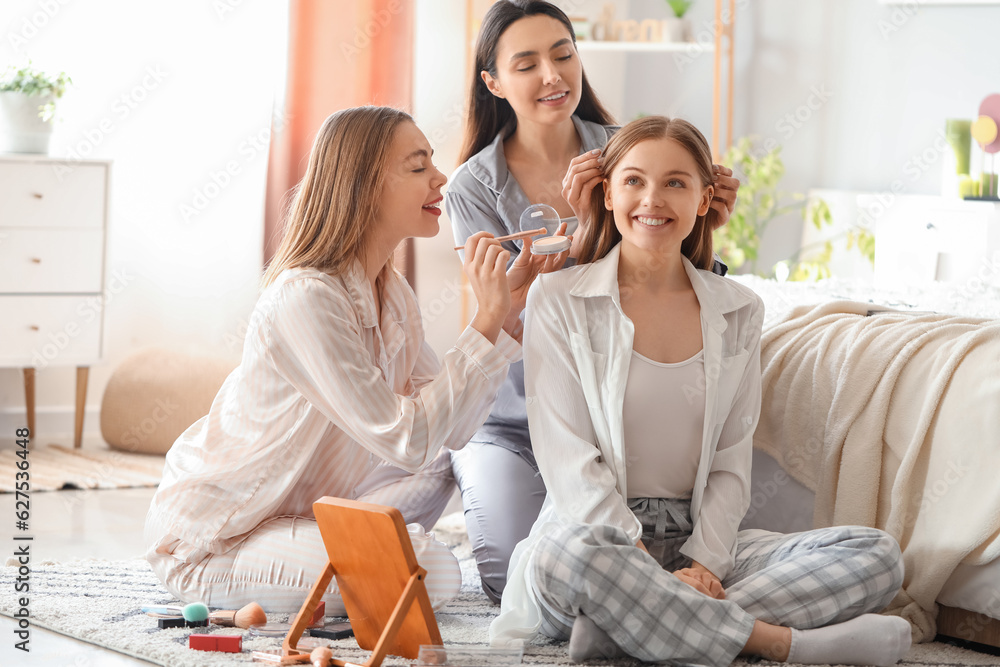 Young women doing makeup in bedroom