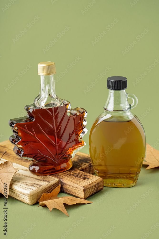 Bottles of maple syrup on green background