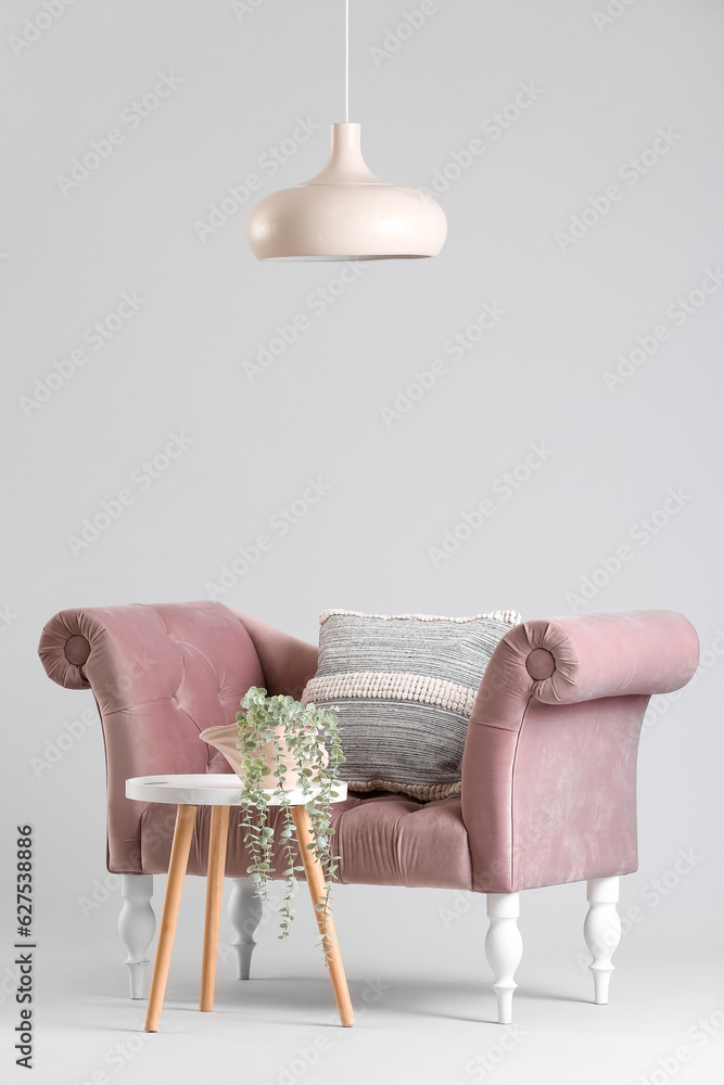 Cozy pink sofa and coffee table with houseplant on grey background