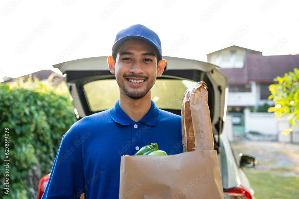 Portrait of delivery in blue uniform handling a box of parcel from car. 