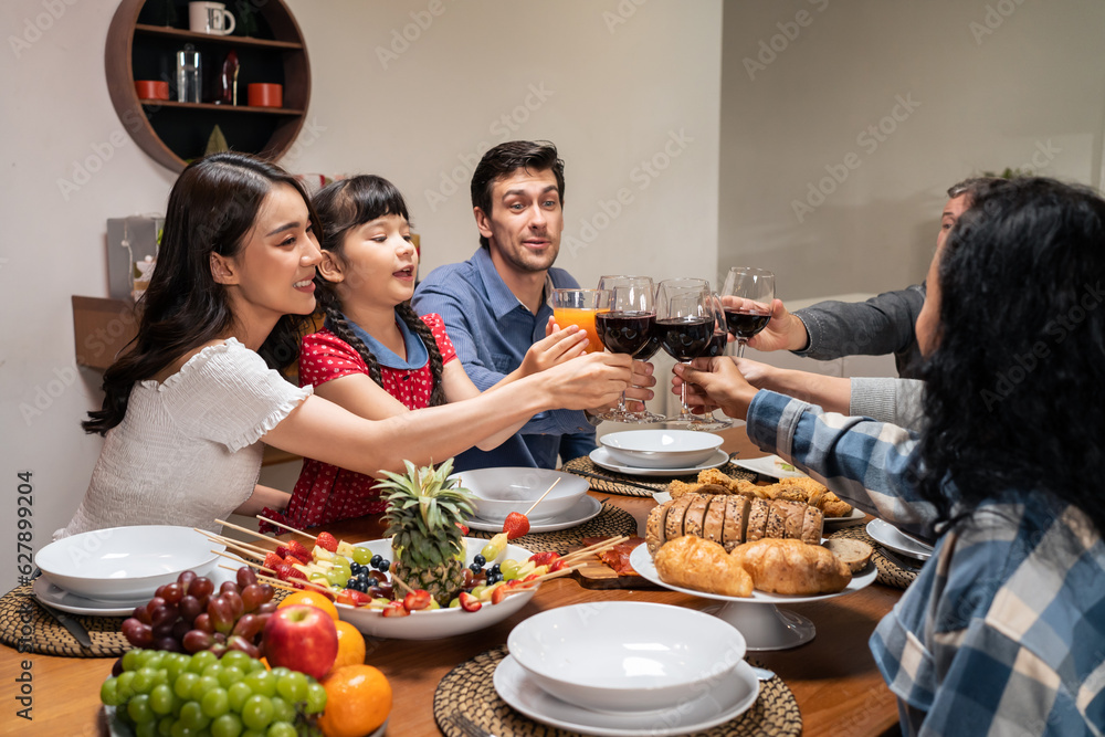 Multi-ethnic big family having dinner, enjoy evening party in house. 