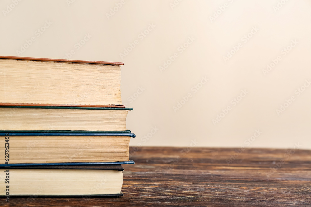 Stack of books on wooden table against beige background