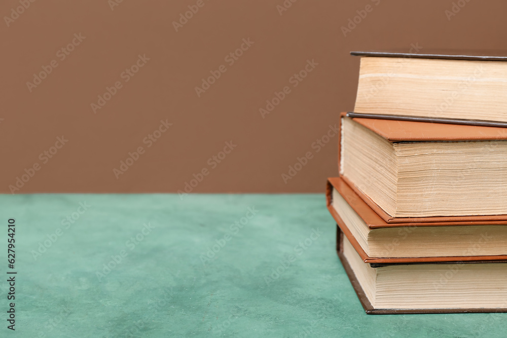 Stack of books on green table against brown background