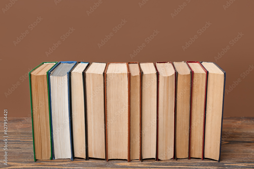 Row of books on wooden table against brown background