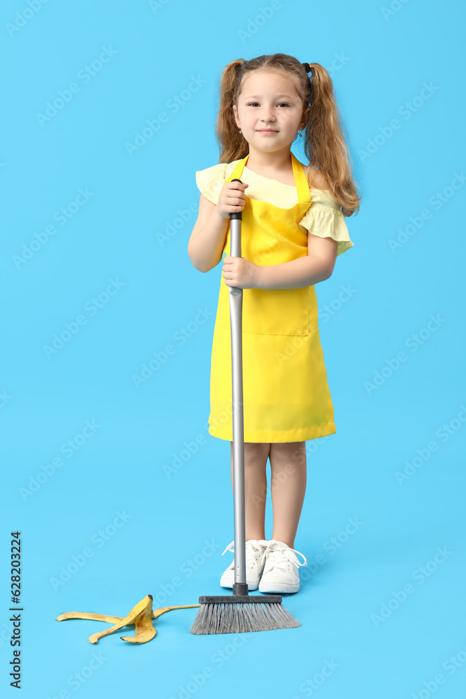 Cute little girl with broom and banana peel on blue background