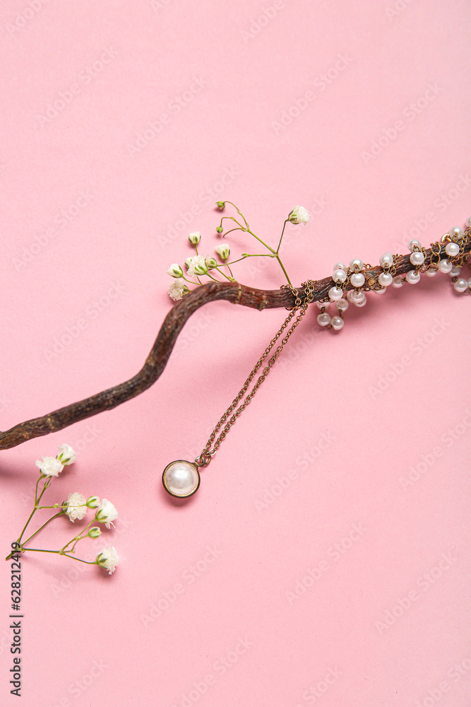 Tree branch with beautiful pearl necklace and gypsophila flowers on pink background