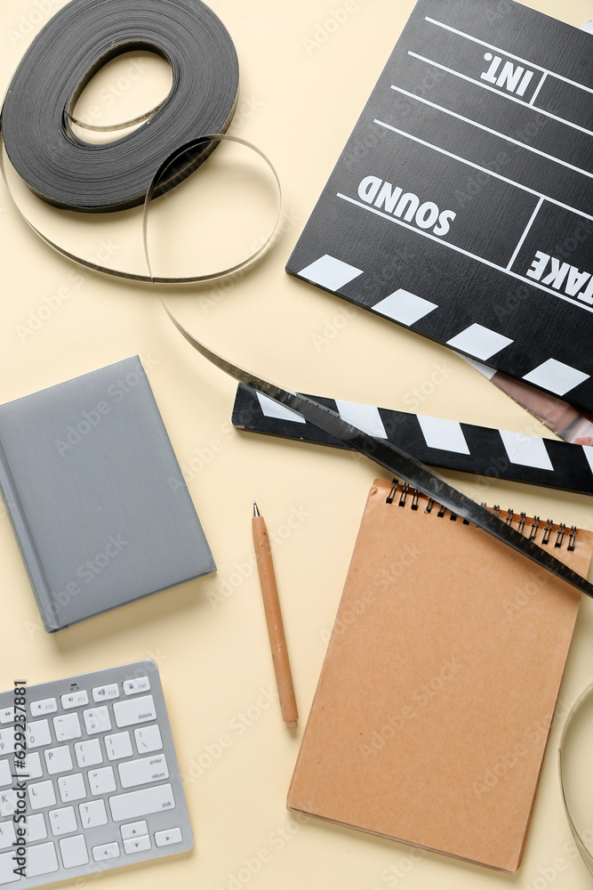 Notebooks with movie clapper and film reel on beige background