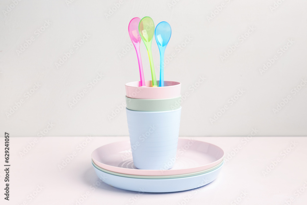 Plates with spoons and cups for baby on white table