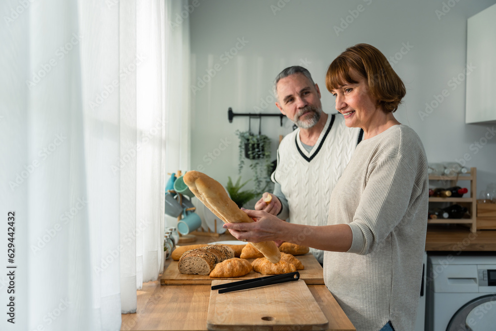 Caucasian senior elderly couple spend time together in kitchen at home. 
