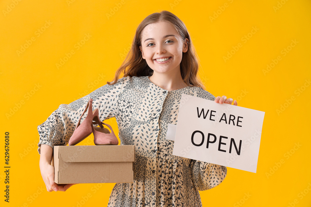 Female seller with shoes and sign with text WE ARE OPEN on yellow background