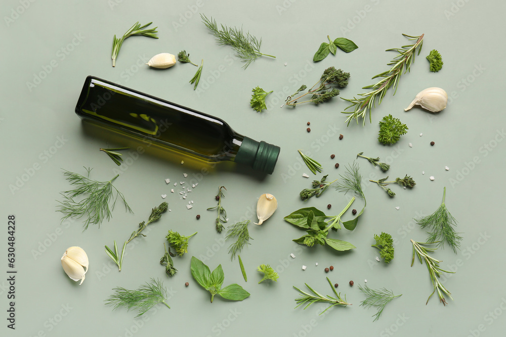 Composition with bottle of olive oil, fresh herbs and spices on color background