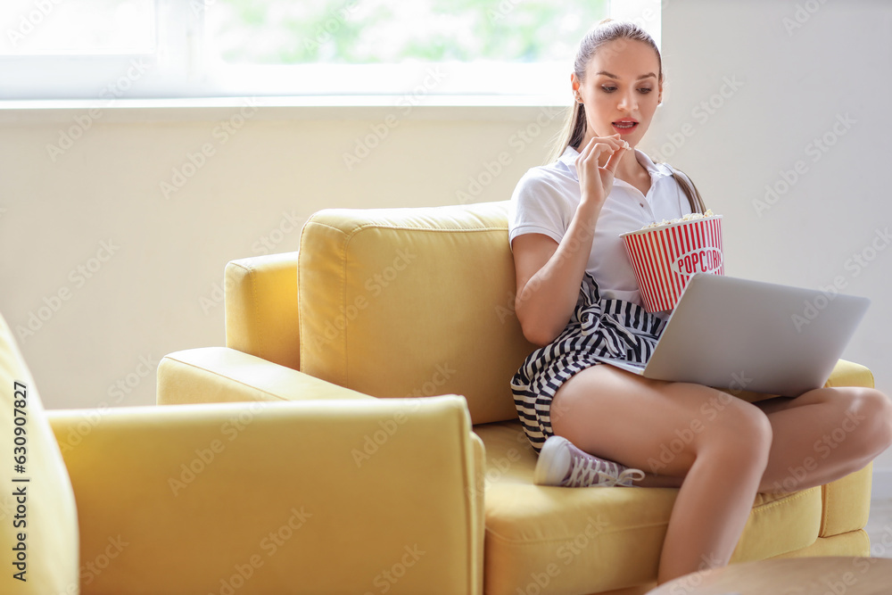 Young woman with popcorn watching movie on her day off at home