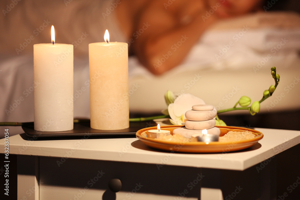 Burning candles, stones and flowers on table in spa salon