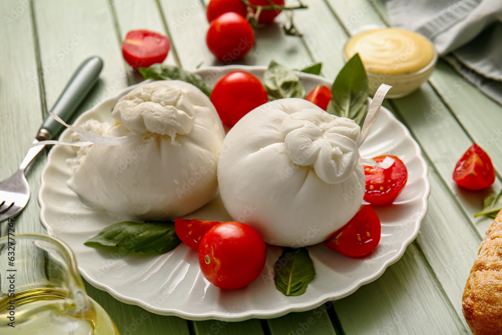 Plate with tasty Burrata cheese on green wooden background