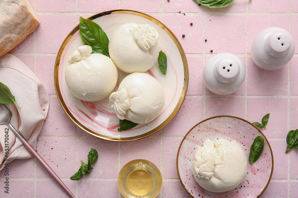 Plates of tasty Burrata cheese with basil on pink tile table
