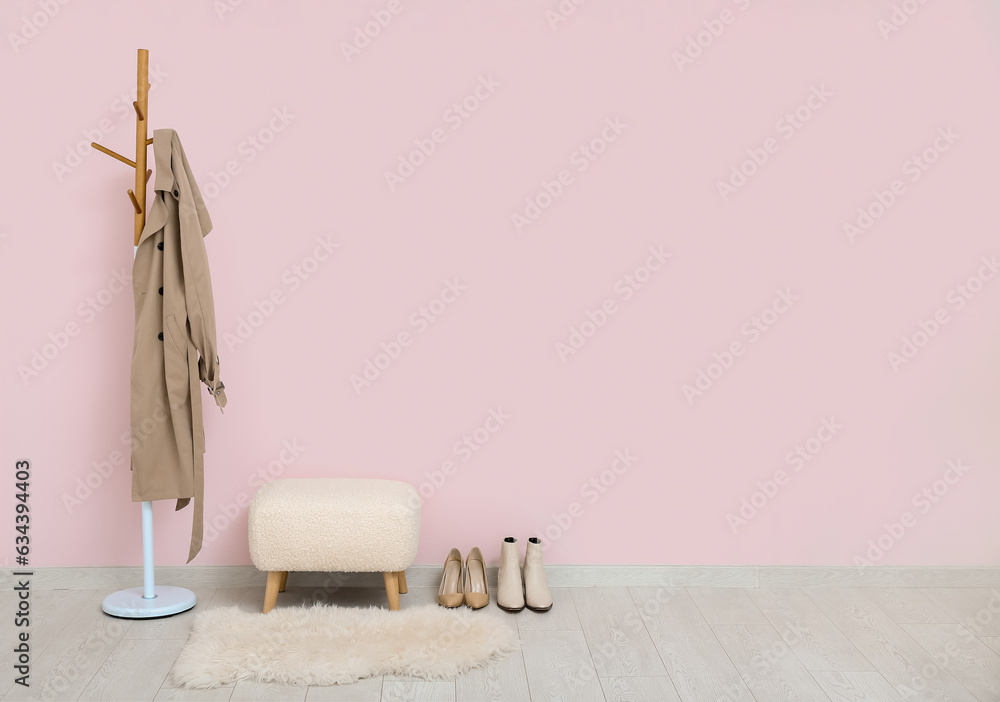 Modern bench, rack with coat and shoes near pink wall in hall