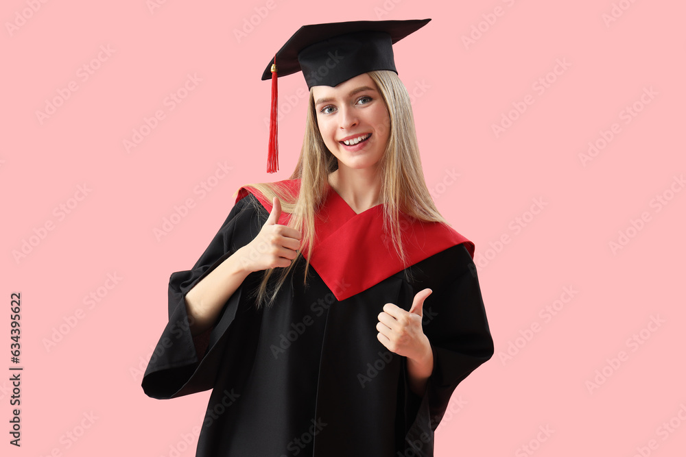 Female graduate student showing thumbs-up on pink background