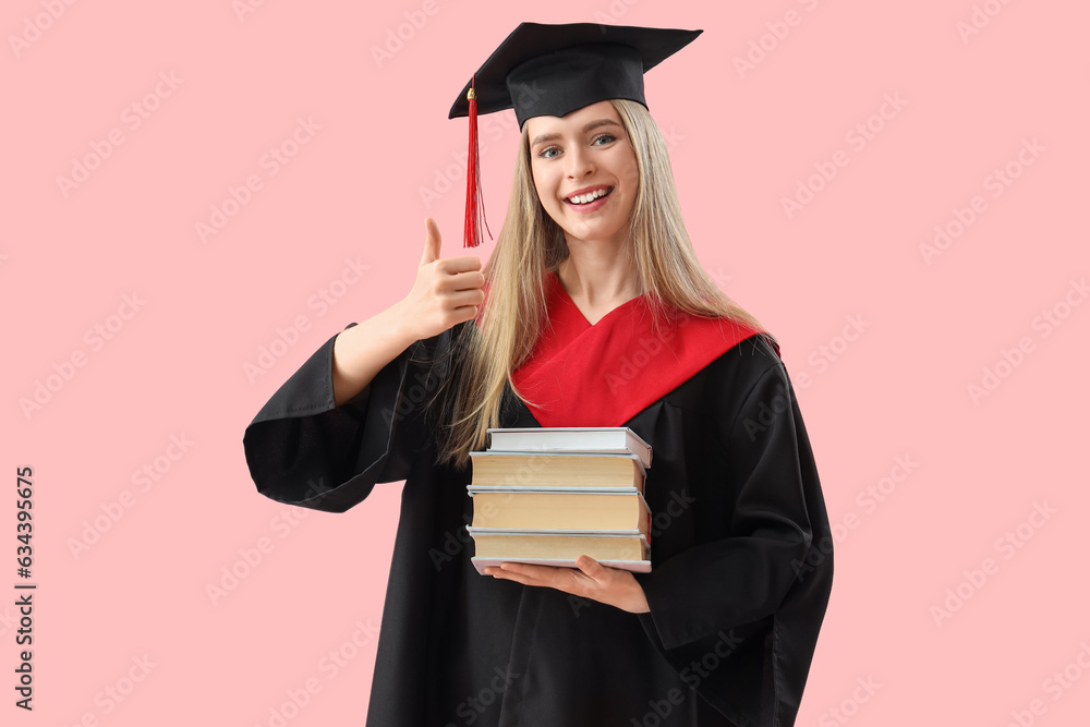 Female graduate student with books showing thumb-up on pink background