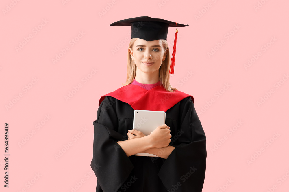 Female graduate student with tablet computer on pink background