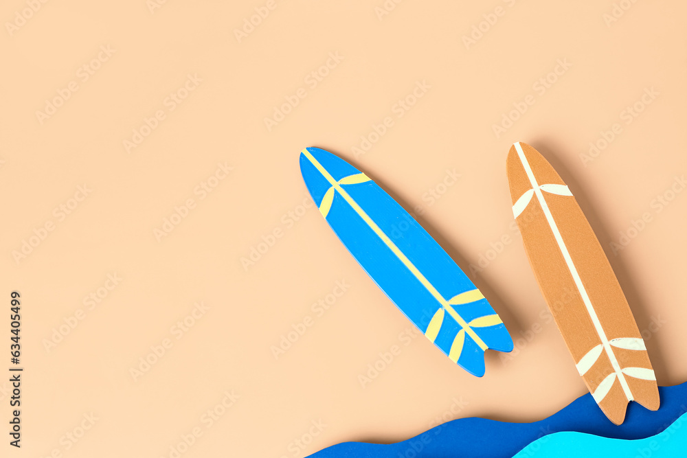 Creative composition with paper waves and mini surfboards on pale orange background
