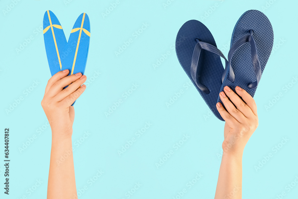 Female hands with mini surfboards and flip flops on blue background