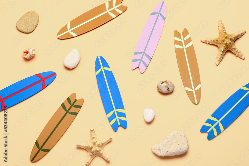 Different mini surfboards, starfishes and stones on yellow background