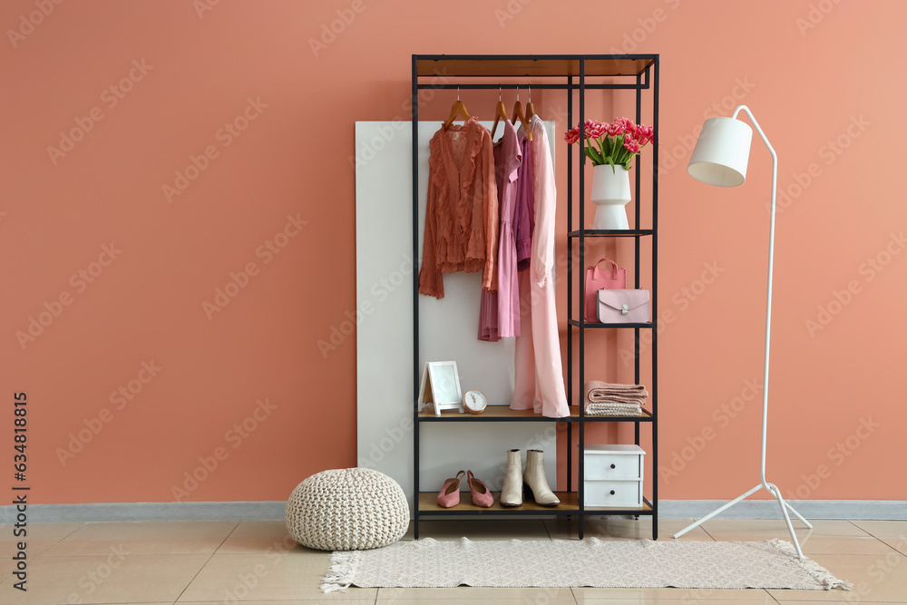 Interior of stylish room with shelving unit, clothes and lamp
