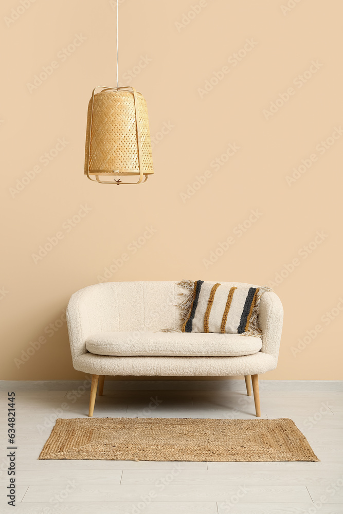 Cozy white sofa, carpet and wicker lamp near orange wall