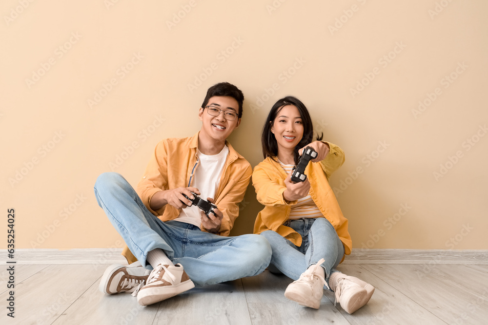 Young Asian friends playing video game near beige wall
