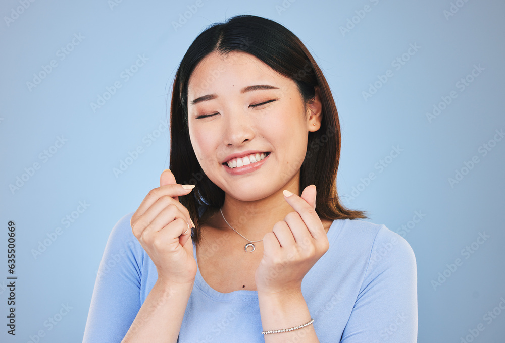 Happy asian woman, hands and love sign or gesture in romance against a blue studio background. Face 