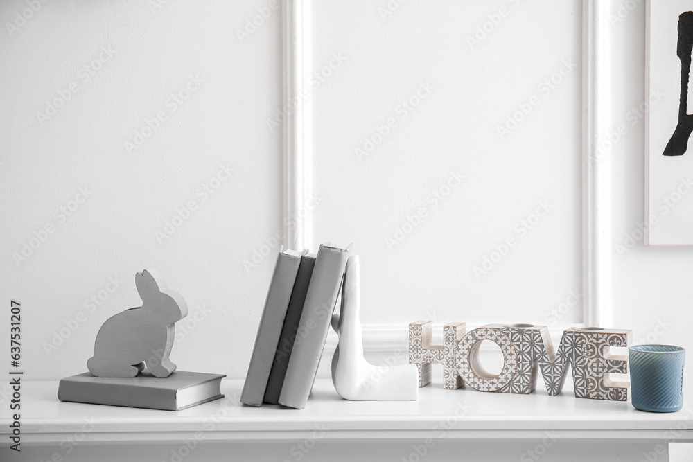Stylish holder for books with different home decor on commode in room