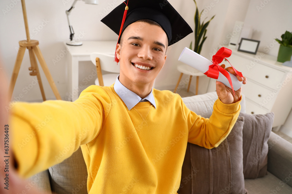 Male graduate student with diploma taking selfie at home