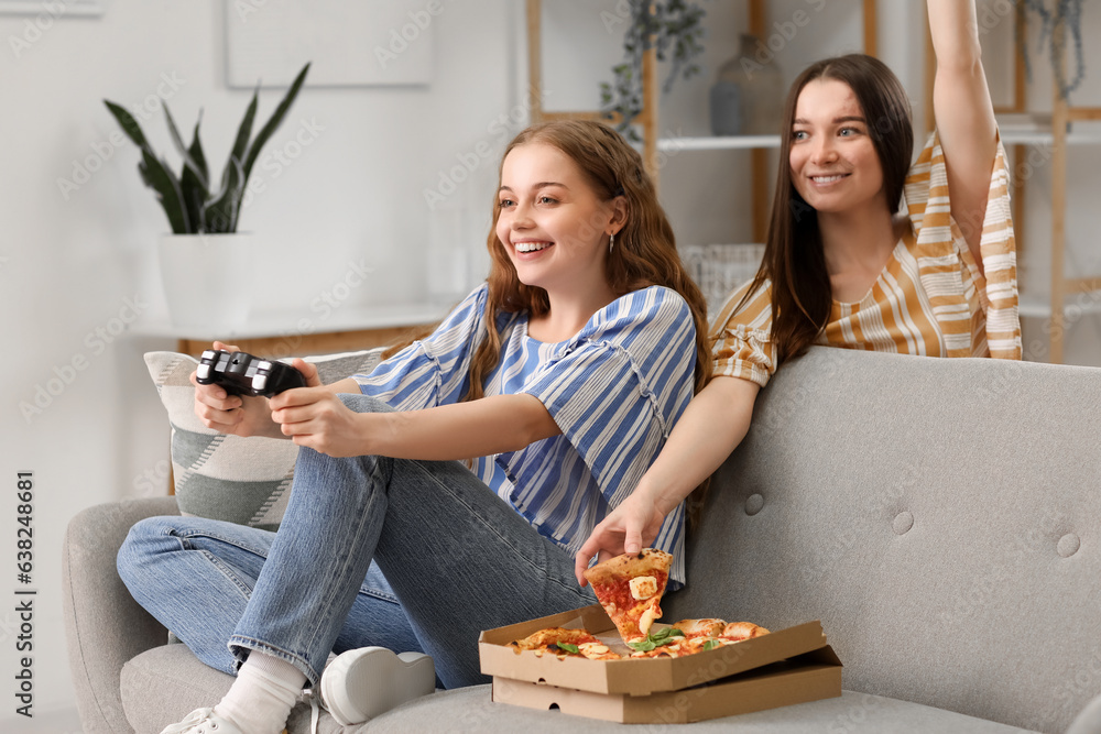 Young women with tasty pizza playing video game at home