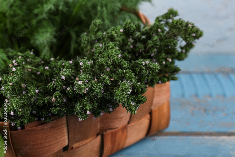 Basket with fresh herbs on color wooden table, closeup