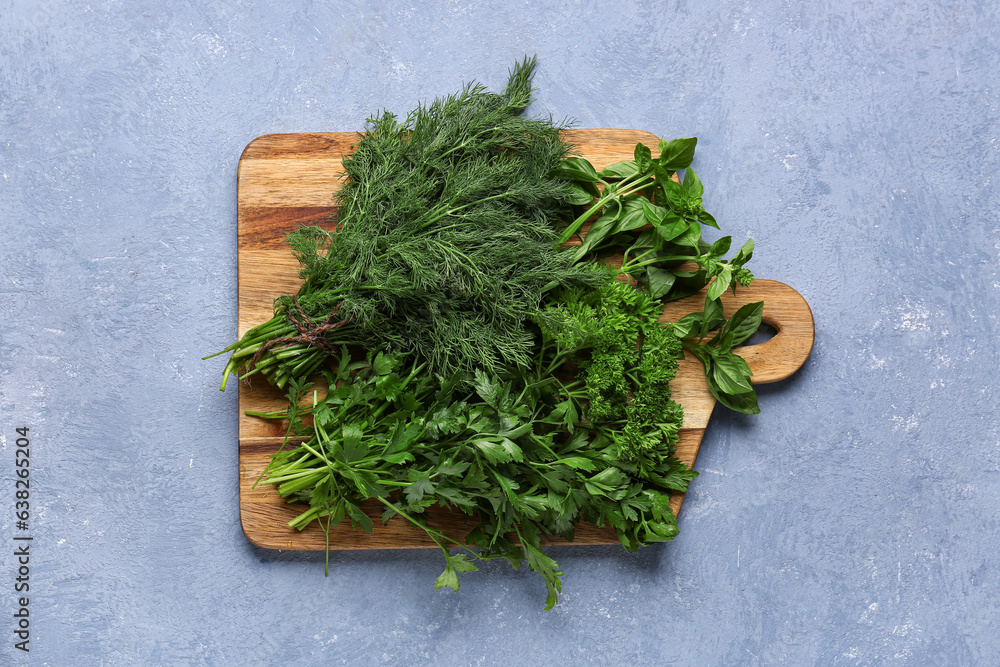 Wooden board with fresh herbs on color background