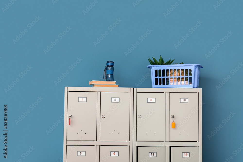 Modern locker with bottle of water and books near blue wall