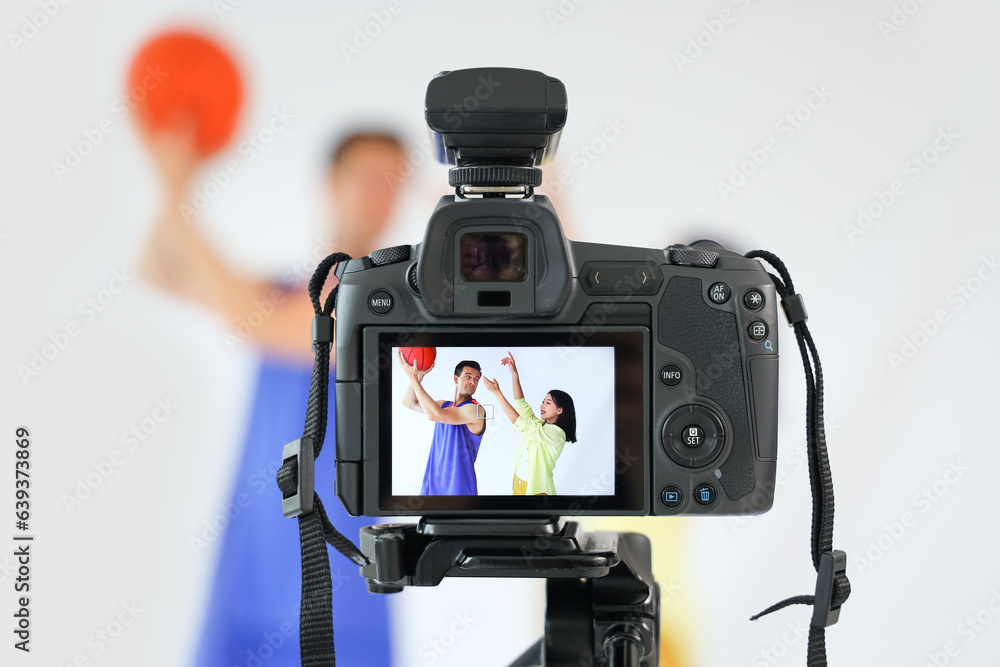 Female photographer working with basketball player on camera screen in studio, closeup
